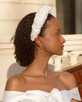 Load image into Gallery viewer, Woman wearing a white bridal headband with a blurred background
