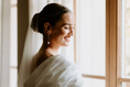 Load image into Gallery viewer, Woman in a white bridal gown with a veil standing by a window wearing pearl bridal earrings
