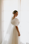 Load image into Gallery viewer, Woman in a white bridal gown with a veil standing by a window wearing pearl bridal earrings
