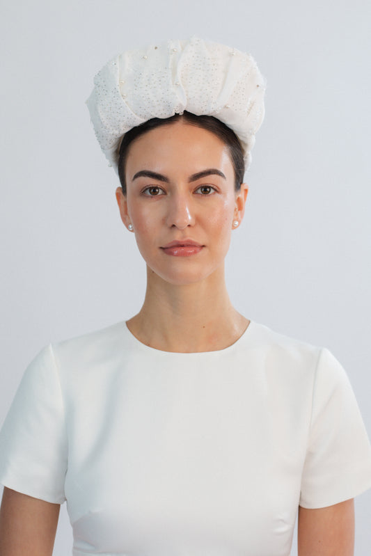 Woman wearing a white bridal headband against a light grey background