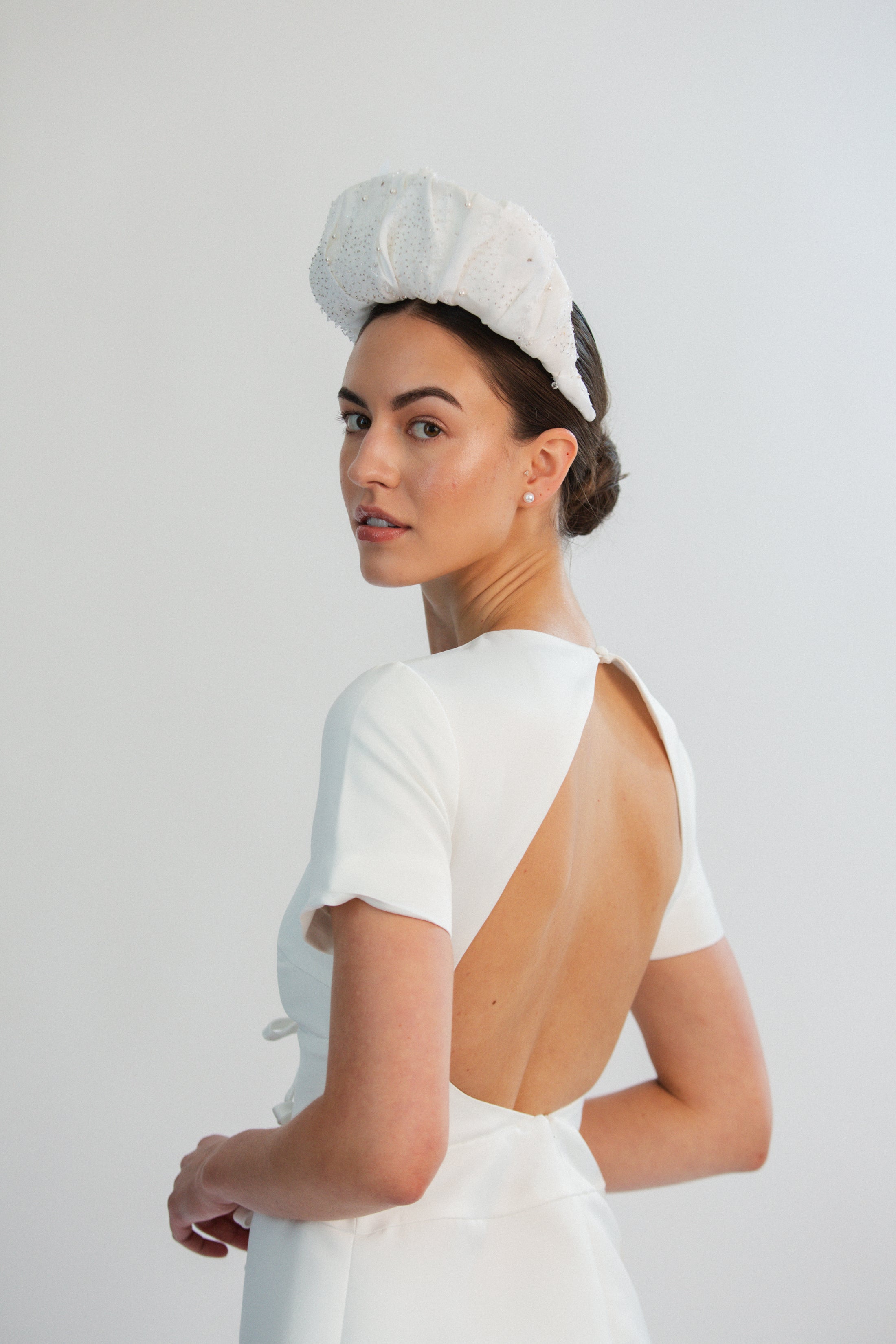 Woman wearing a white bridal headband against a light grey background