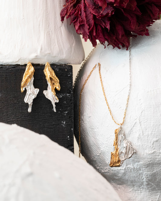 Jewelry set with earrings and a necklace displayed on a white and black stand.