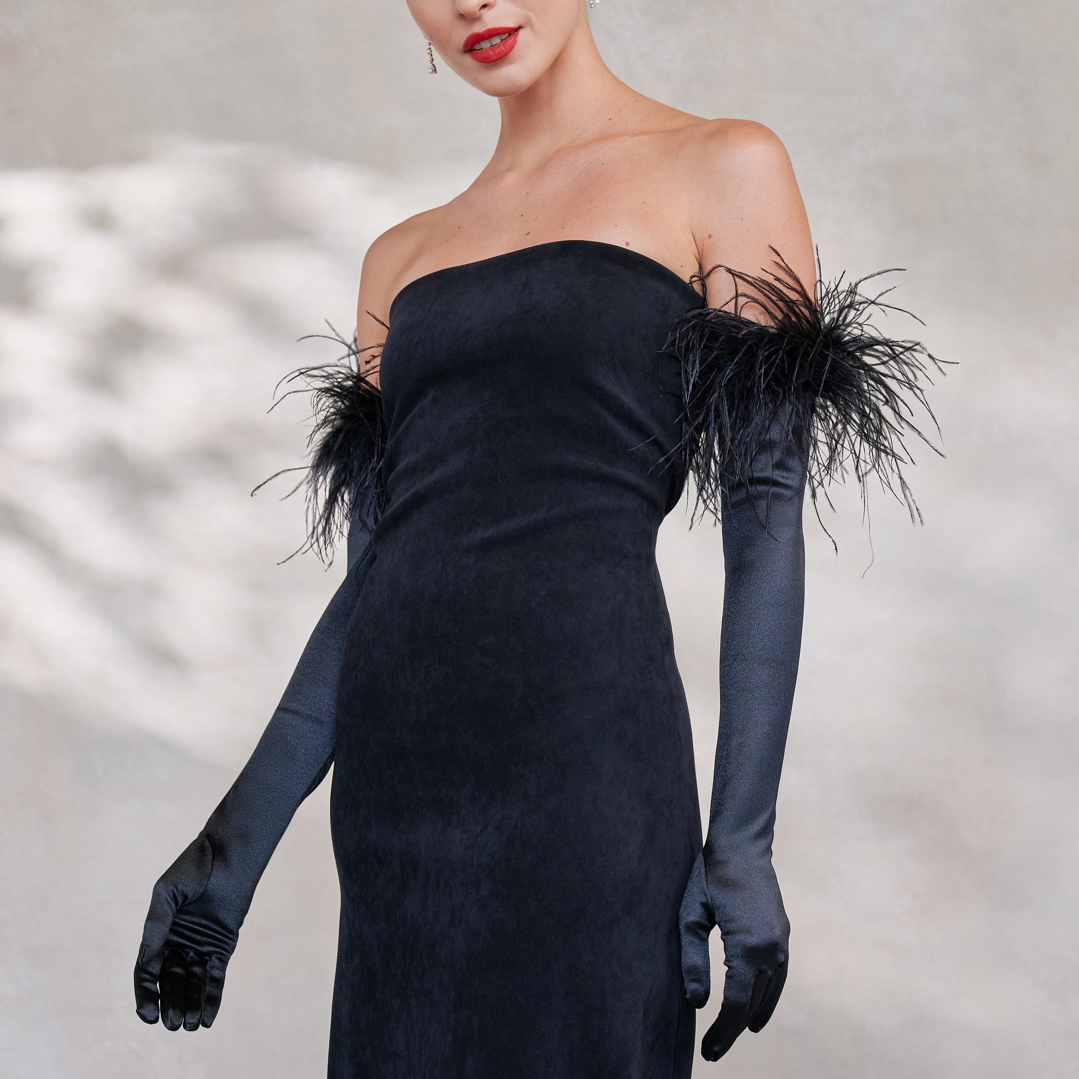 Black strapless dress with feathered shoulders and black opera satin gloves with ostrich feather cuff