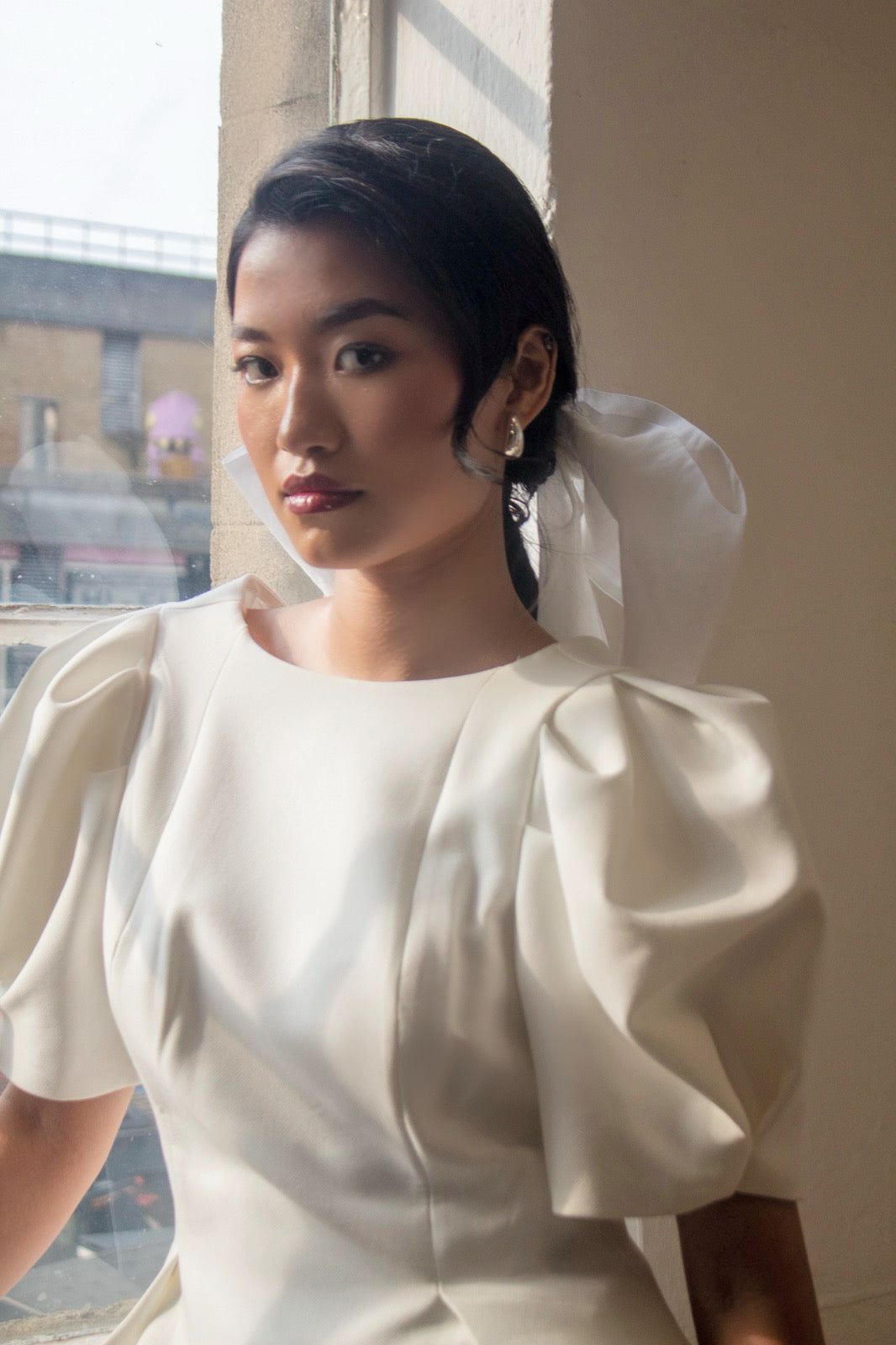Woman wearing a white dress with puffed sleeves in an indoor setting.
