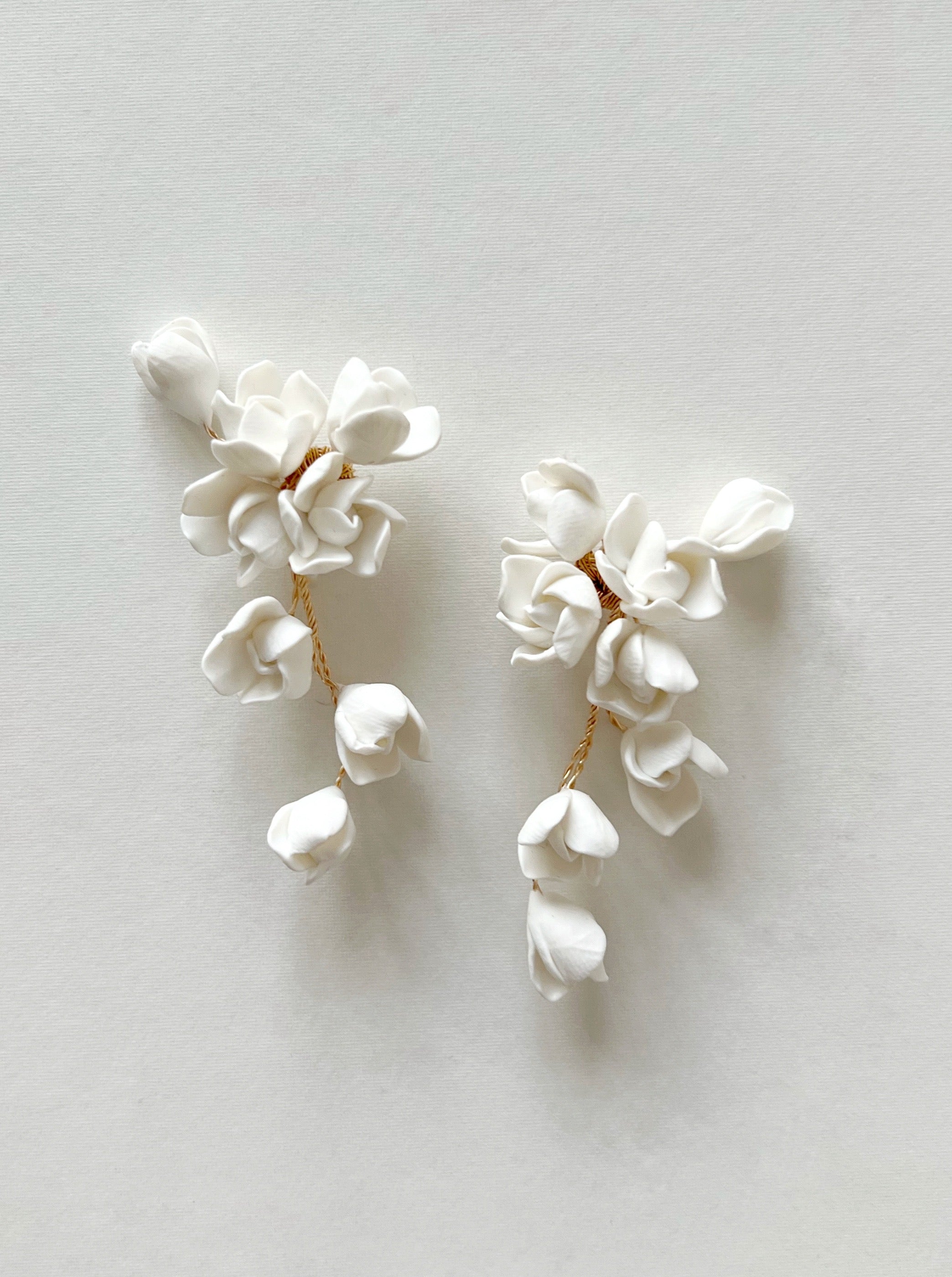 Pair of white floral earrings on a light gray background