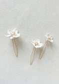 Load image into Gallery viewer, Two white floral hairpins with gold accents on a light gray background
