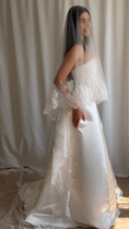 Load image into Gallery viewer, Bride wearing a white wedding dress with a lace veil against a white curtain background.
