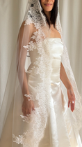 Load image into Gallery viewer, Bride wearing a white wedding dress with a lace veil against a white curtain background.
