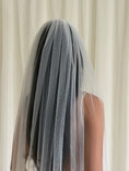 Load image into Gallery viewer, Person wearing a white wedding dress with a long plain veil against a plain background
