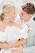 Load image into Gallery viewer, a married couple with the woman wearing a white off-shoulder dress against a city background wearing silk flower bridal earrings
