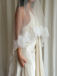 Load image into Gallery viewer, Bride wearing a white wedding dress with a lace veil against a white curtain background.
