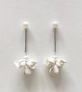 Load image into Gallery viewer, Pair of white floral earrings on a light gray background
