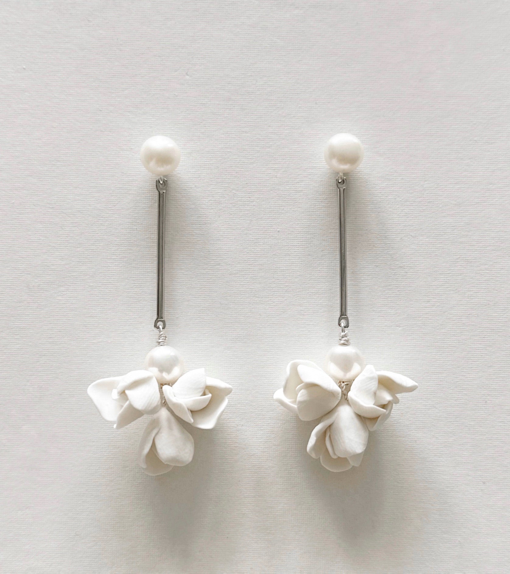 Pair of white floral earrings on a light gray background
