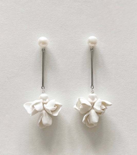 Pair of white floral earrings on a light gray background