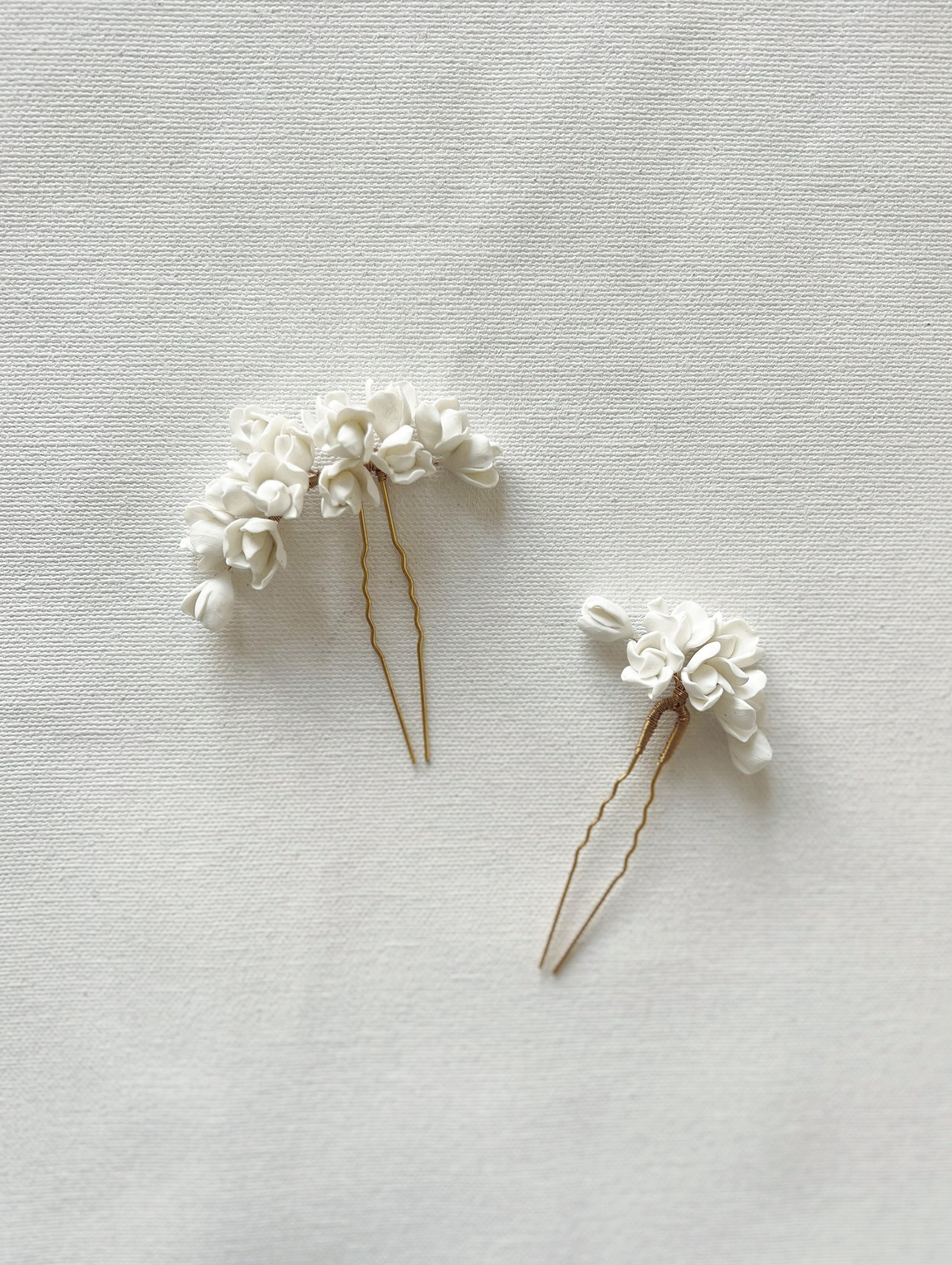 Two white floral hairpins on a light gray background