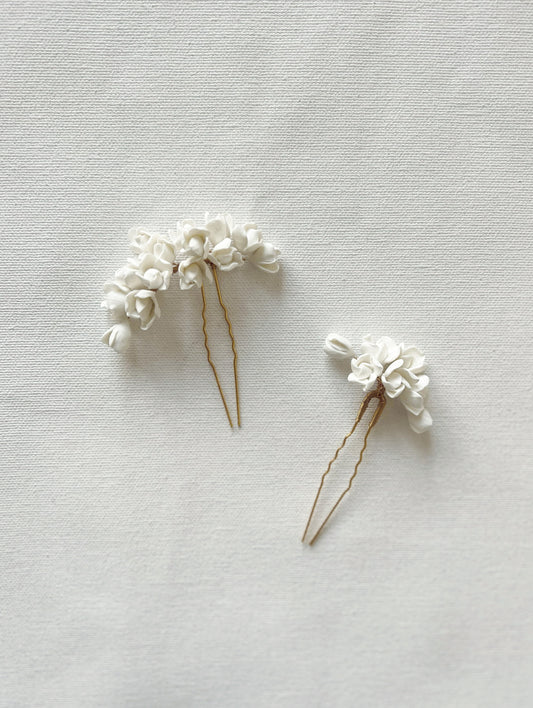 Two white floral hairpins on a light gray background