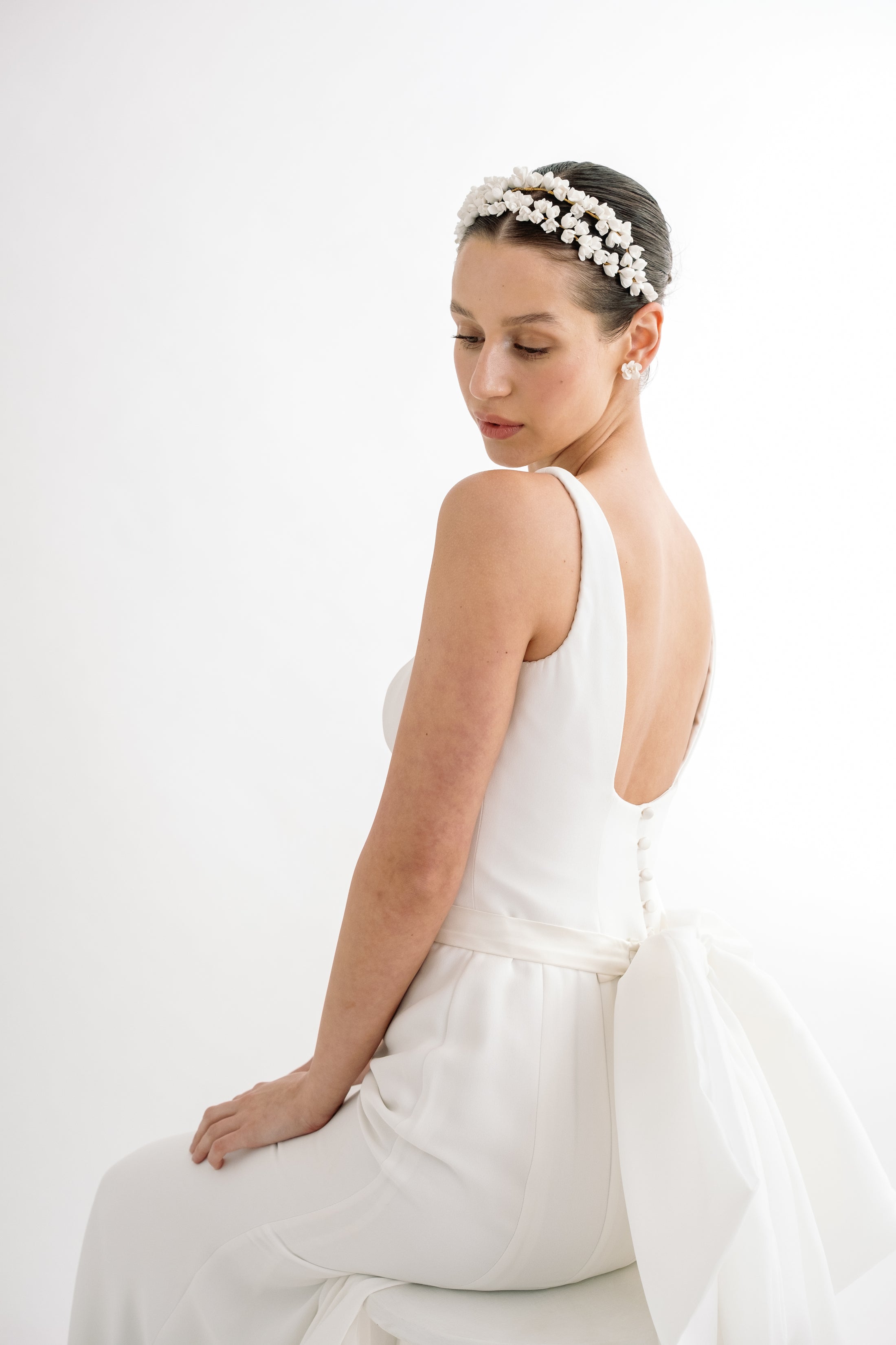 Woman wearing a white dress and floral headband on a white background