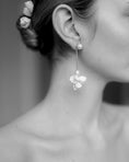 Load image into Gallery viewer, Close-up of a person wearing floral earrings with a blurred background
