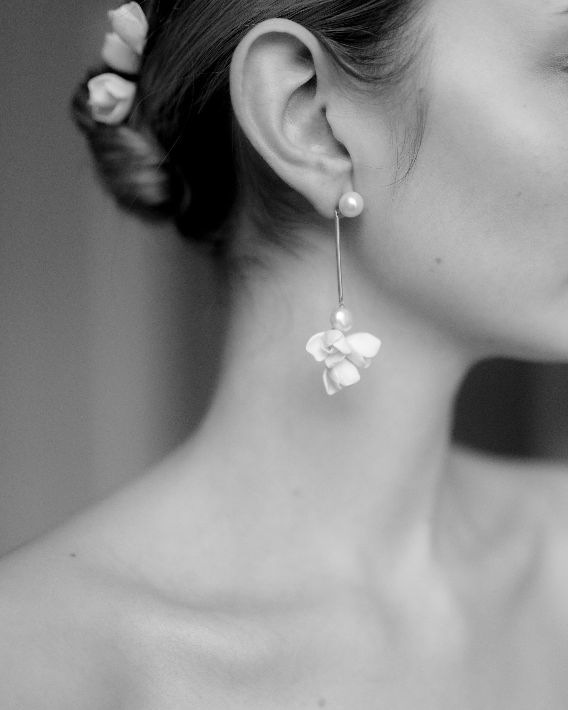 Close-up of a person wearing floral earrings with a blurred background