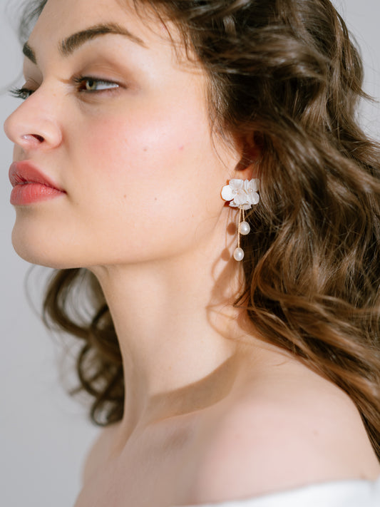 Close-up of a woman wearing floral earrings with a neutral background