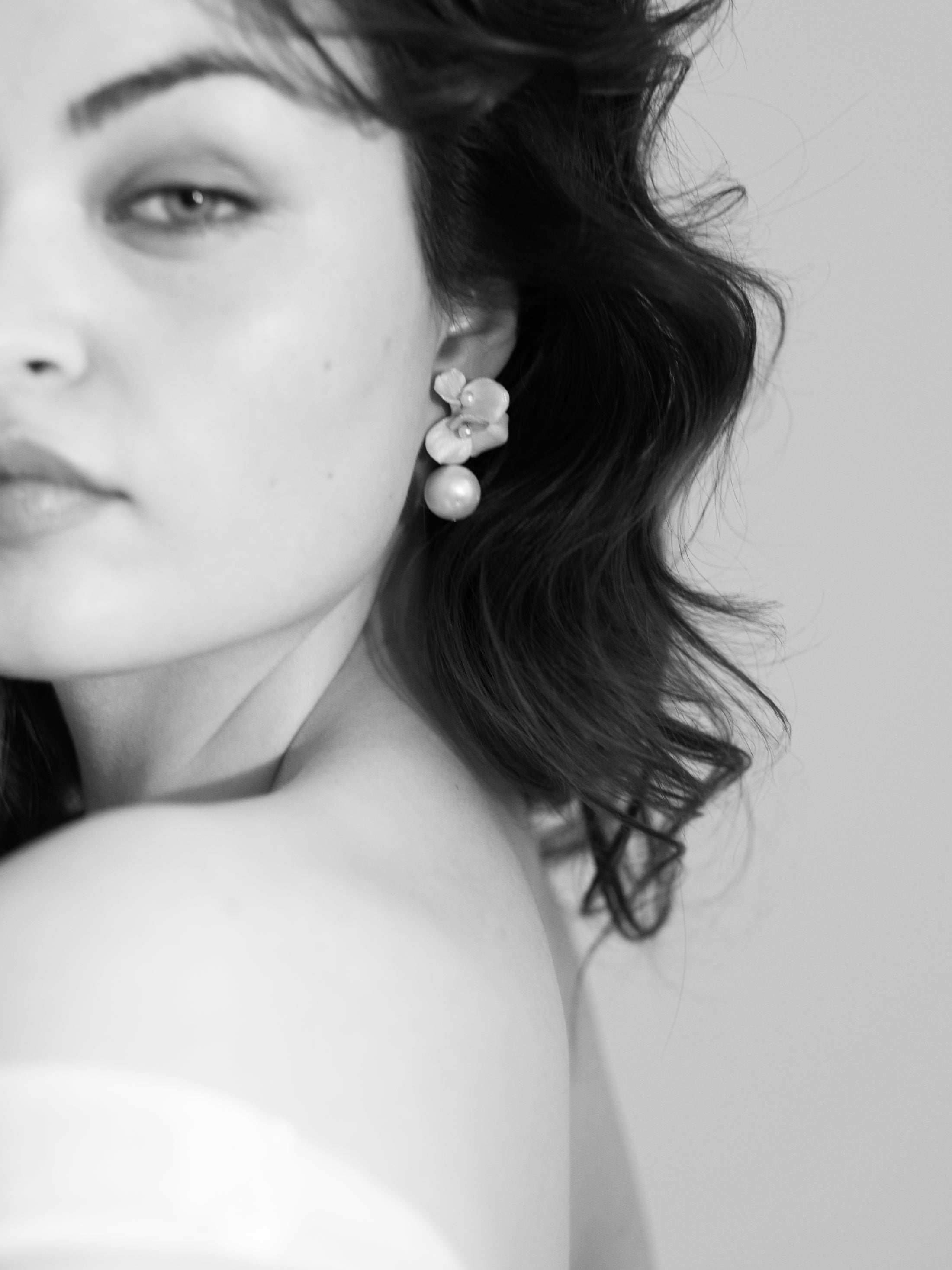 Close-up of a woman wearing floral earrings with a neutral background