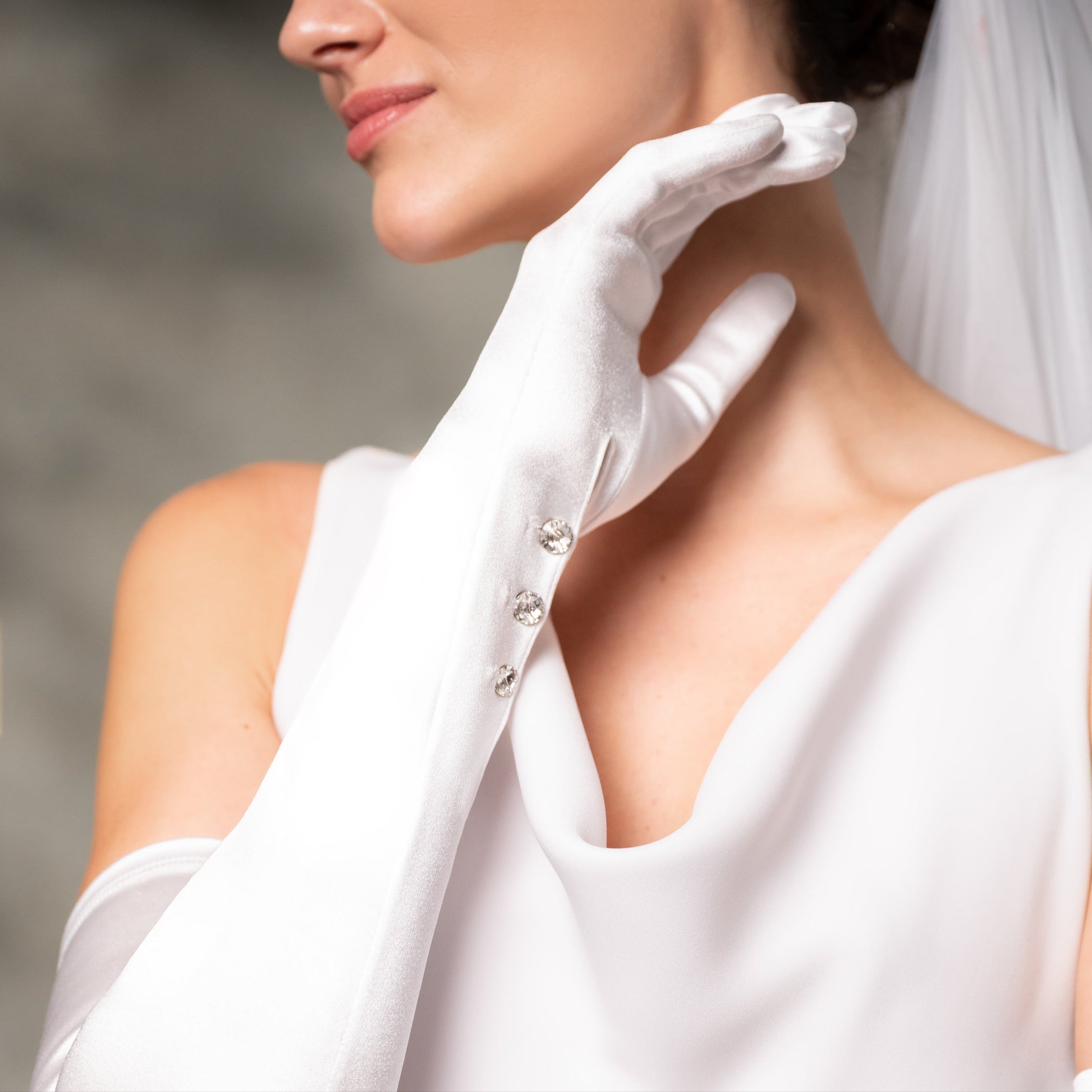 Close-up of bride wearing a white glove with a blurred background