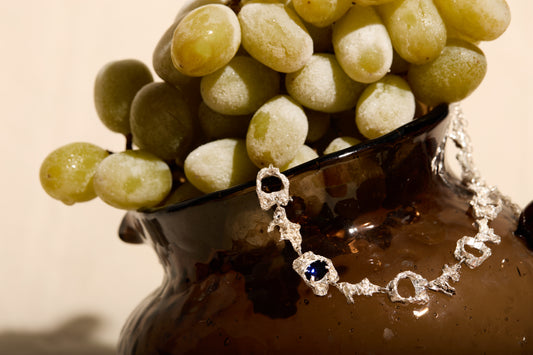 bracelet with a sapphire displayed on a bowl of grapes