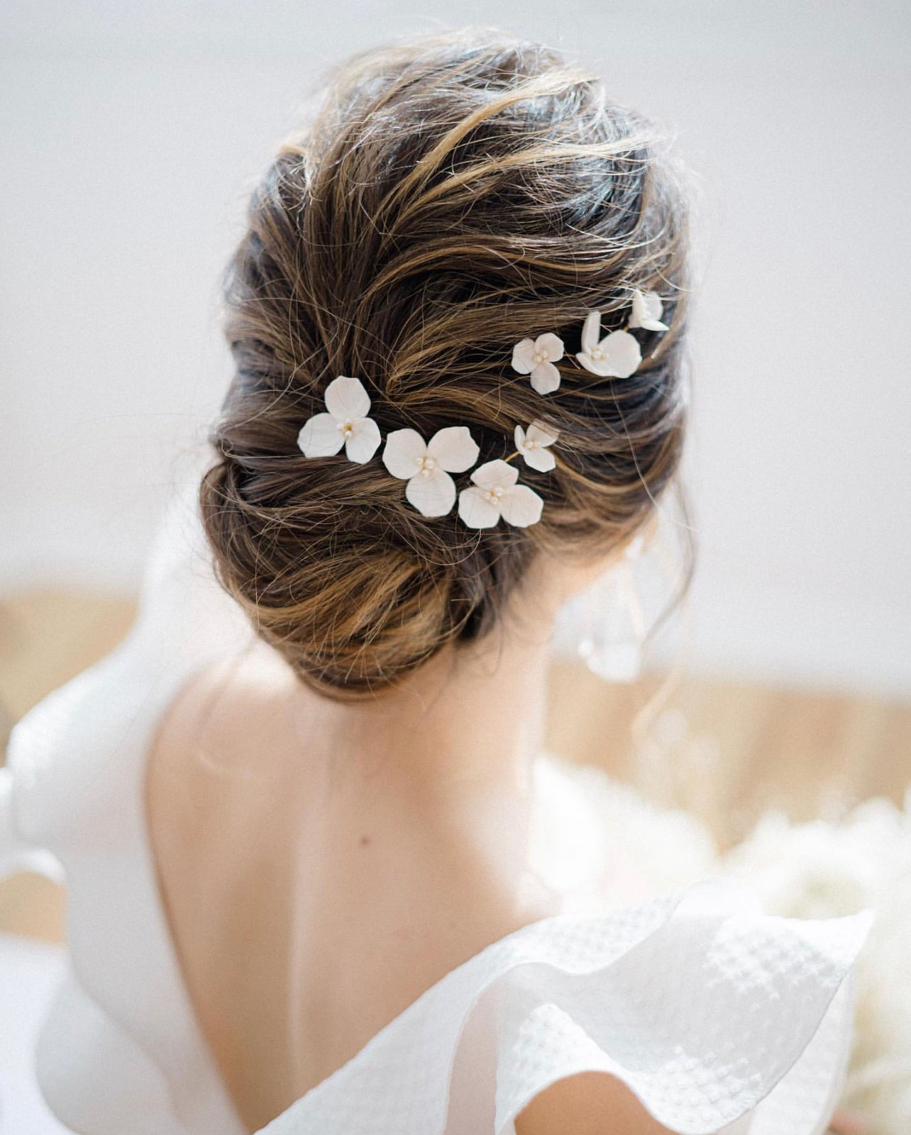 Woman with elegant hair styled with floral hairpins against a neutral background
