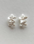 Load image into Gallery viewer, Pair of white floral earrings on a light gray background
