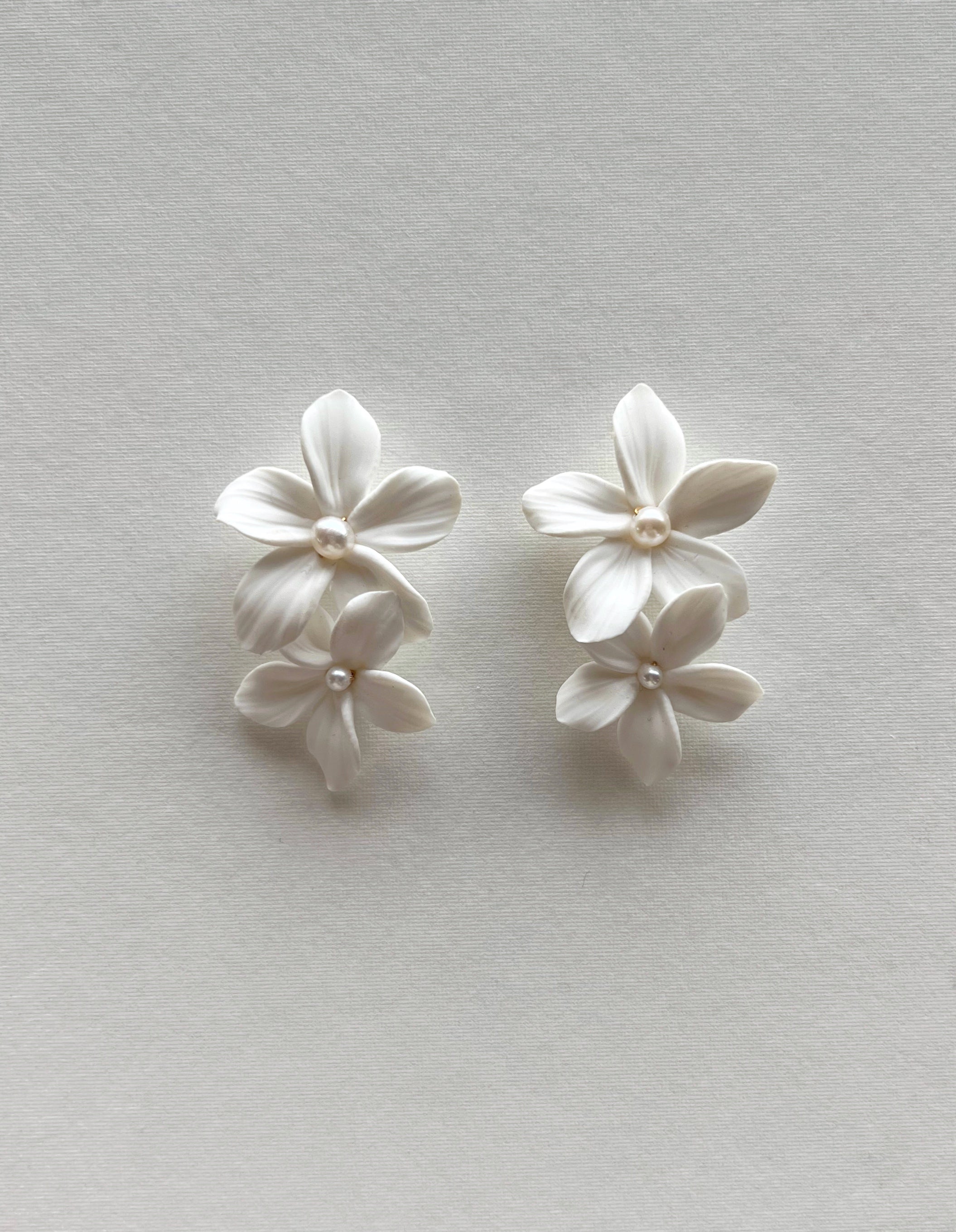 Pair of white floral earrings on a light gray background