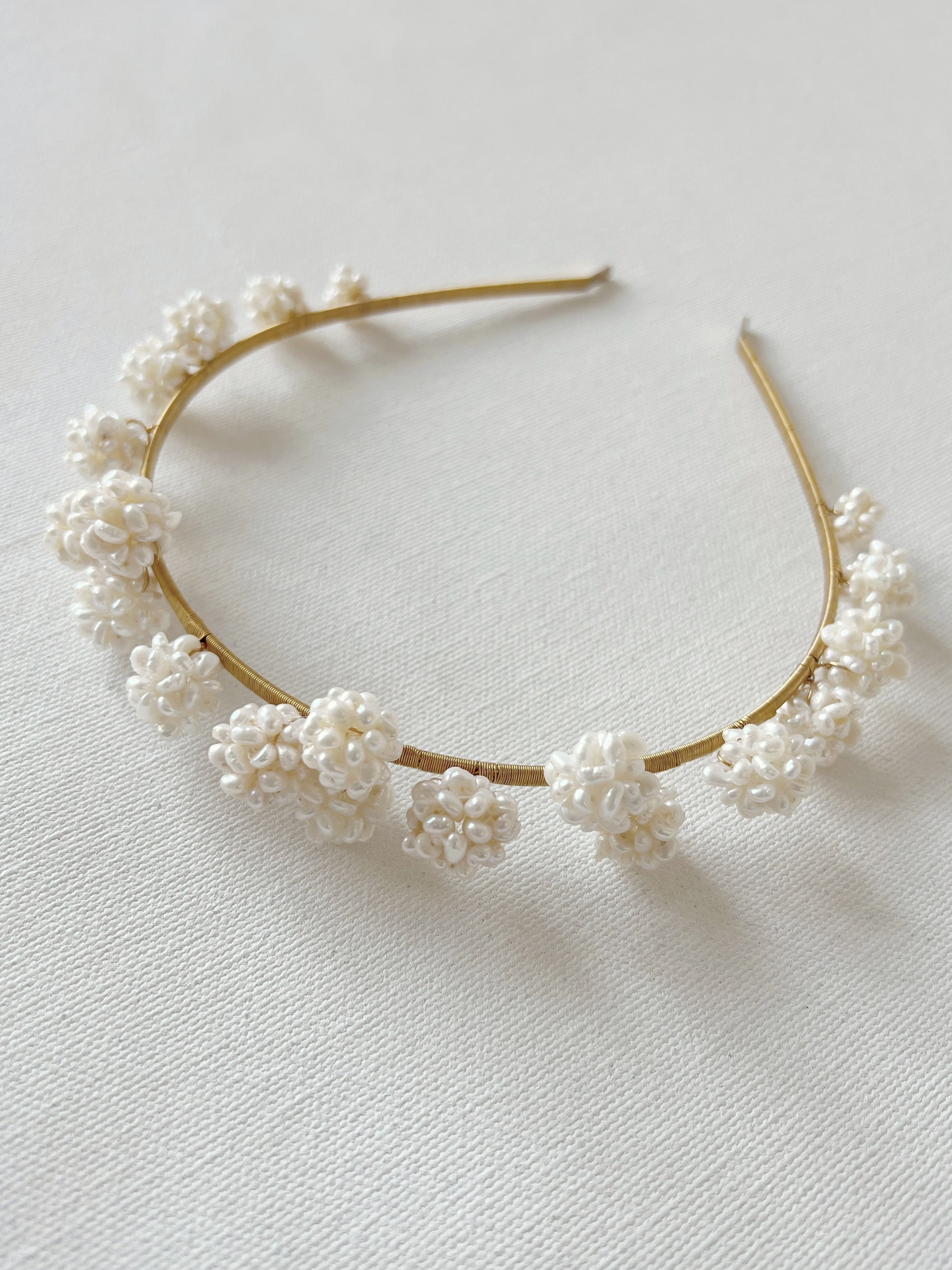 Gold headband with white floral embellishments on a light background