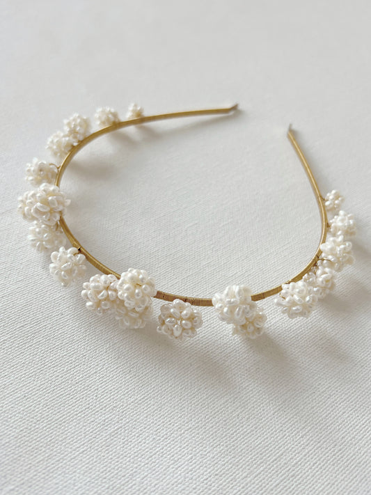Gold headband with white floral embellishments on a light background