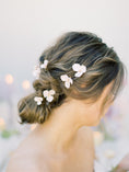Load image into Gallery viewer, Woman with styled hair featuring white flowers against a blurred background
