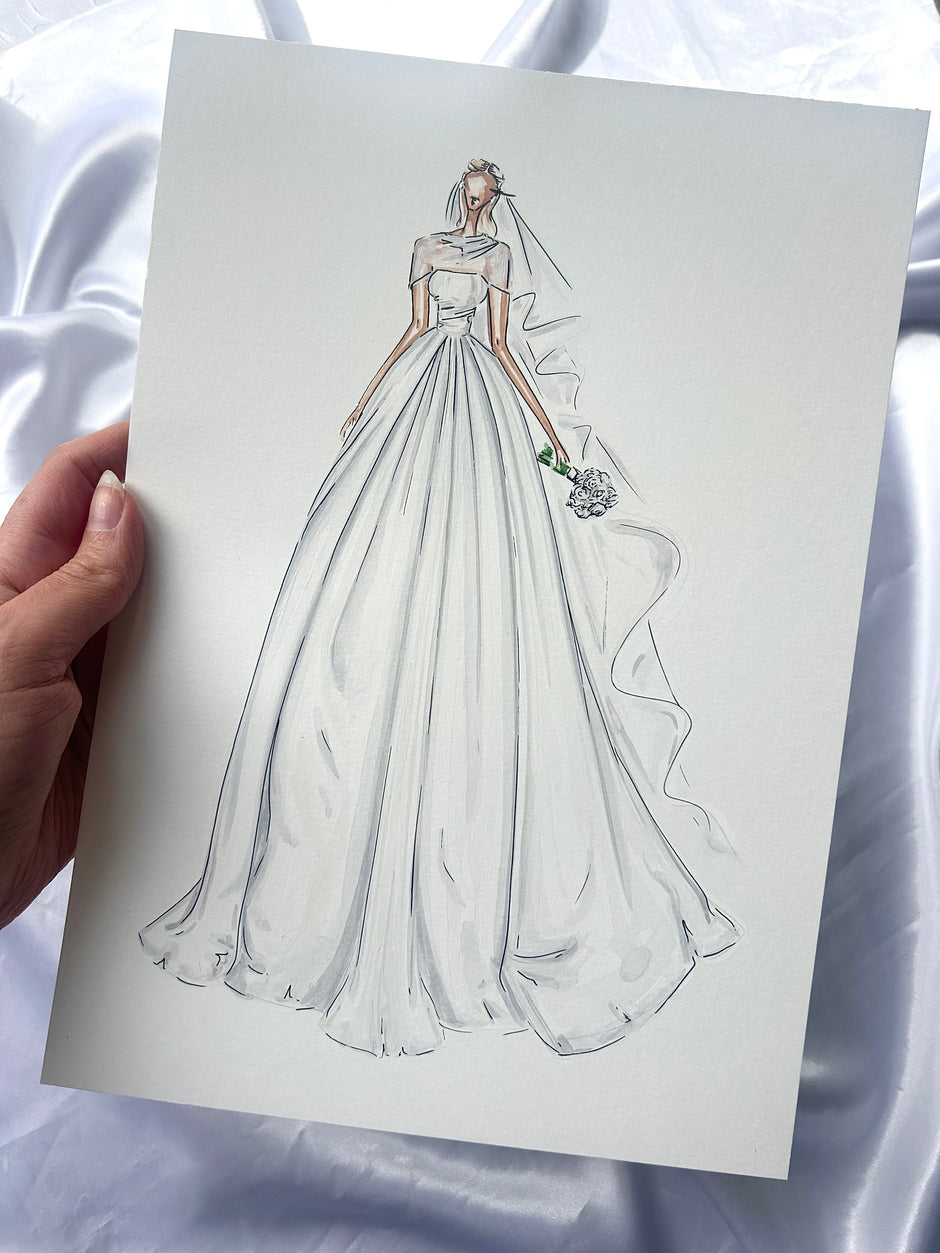 A hand holds a fashion sketch card featuring a hand-drawn illustration of a bride in a voluminous white wedding gown with a veil, set against a draped white satin fabric background.