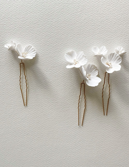 Two floral hair pins on a light gray background