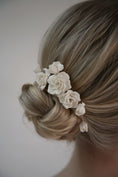Load image into Gallery viewer, Blonde hair with a floral hair accessory against a neutral background
