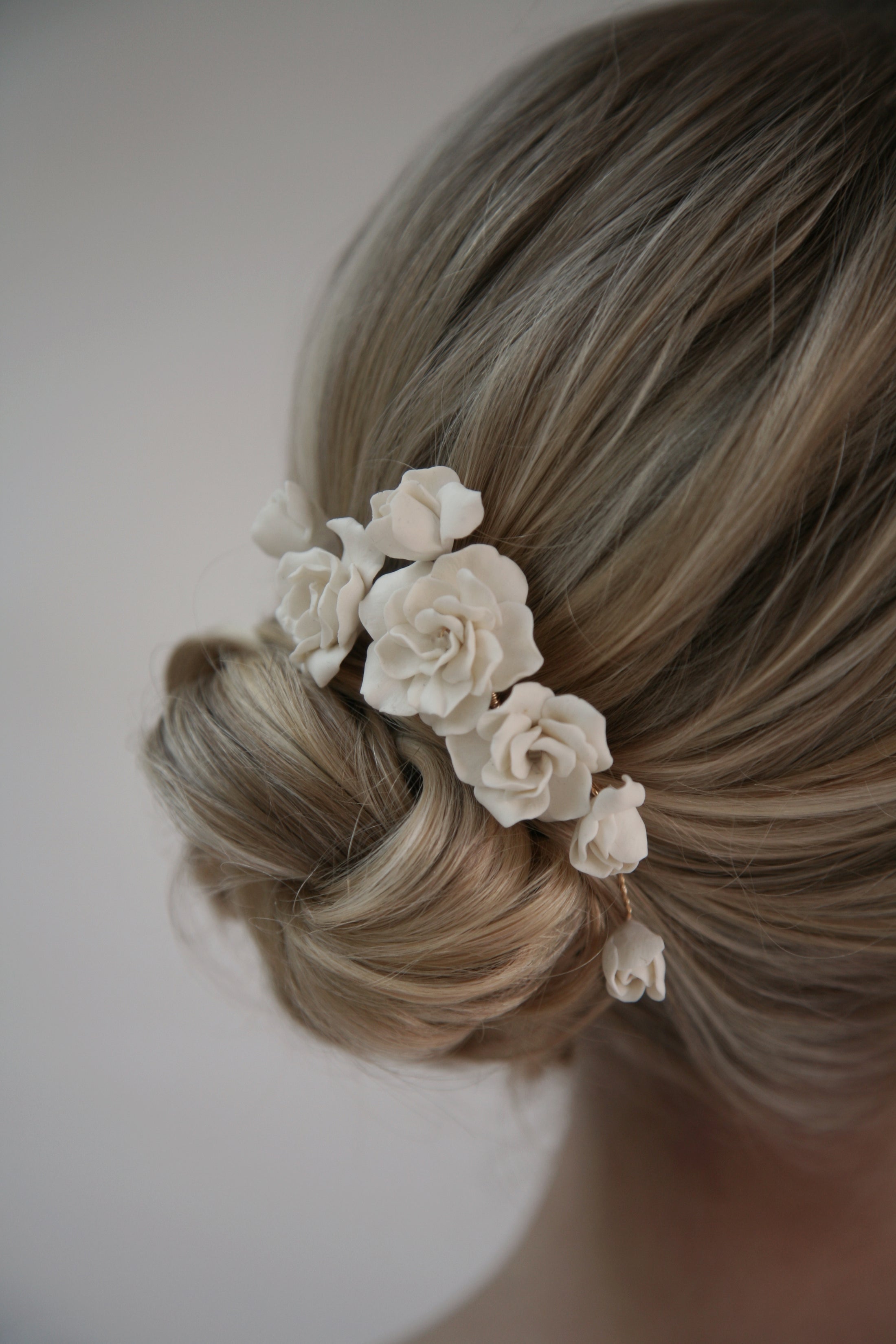 Blonde hair with a floral hair accessory against a neutral background