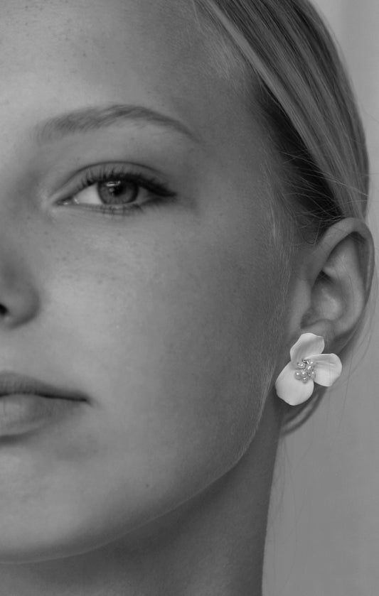 Close-up of a woman wearing a floral earring with a clear gemstone.