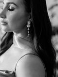 Load image into Gallery viewer, Black and white close-up of a woman wearing elegant earrings with a blurred background

