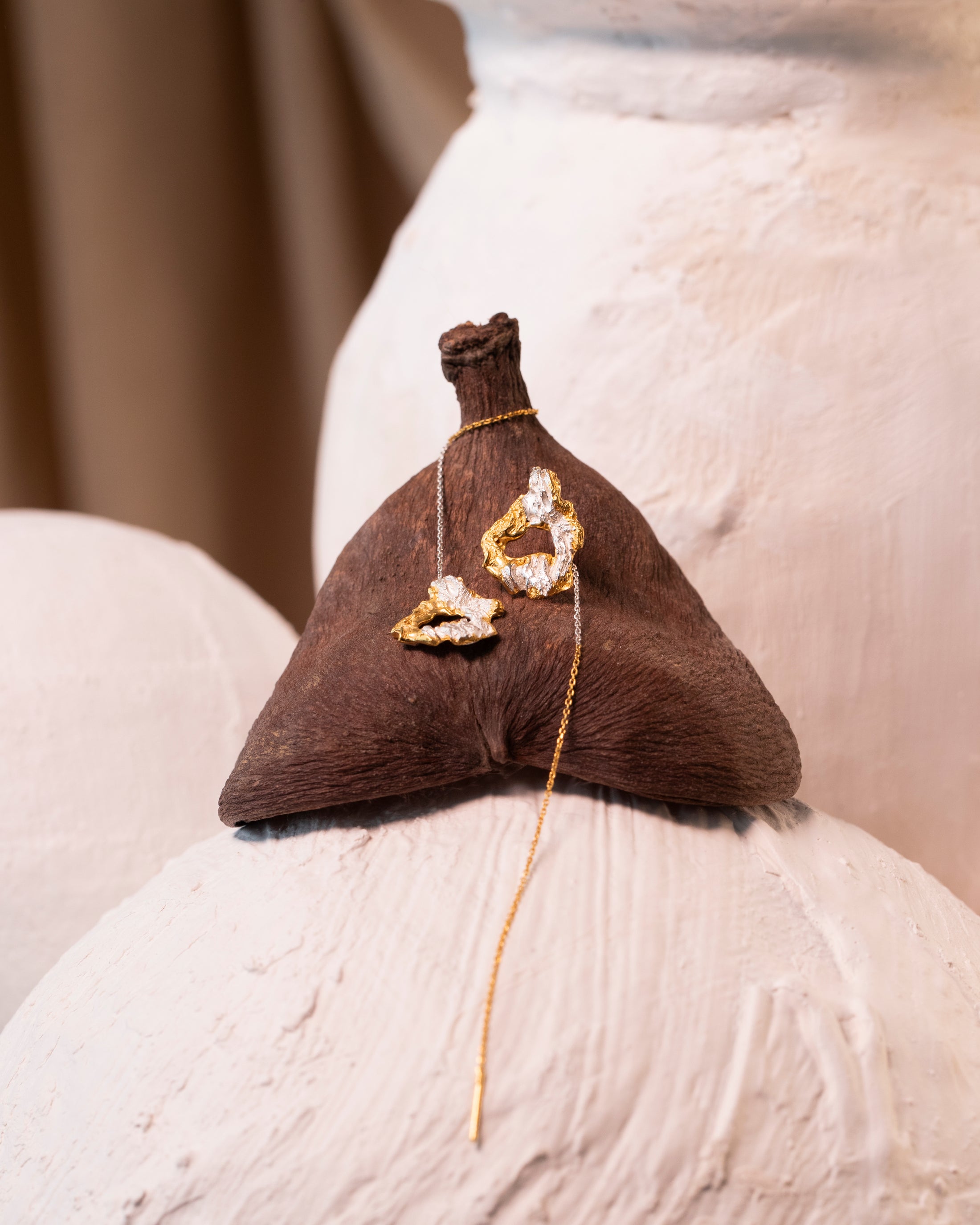 Jewelry on a cone-shaped brown object against a neutral background