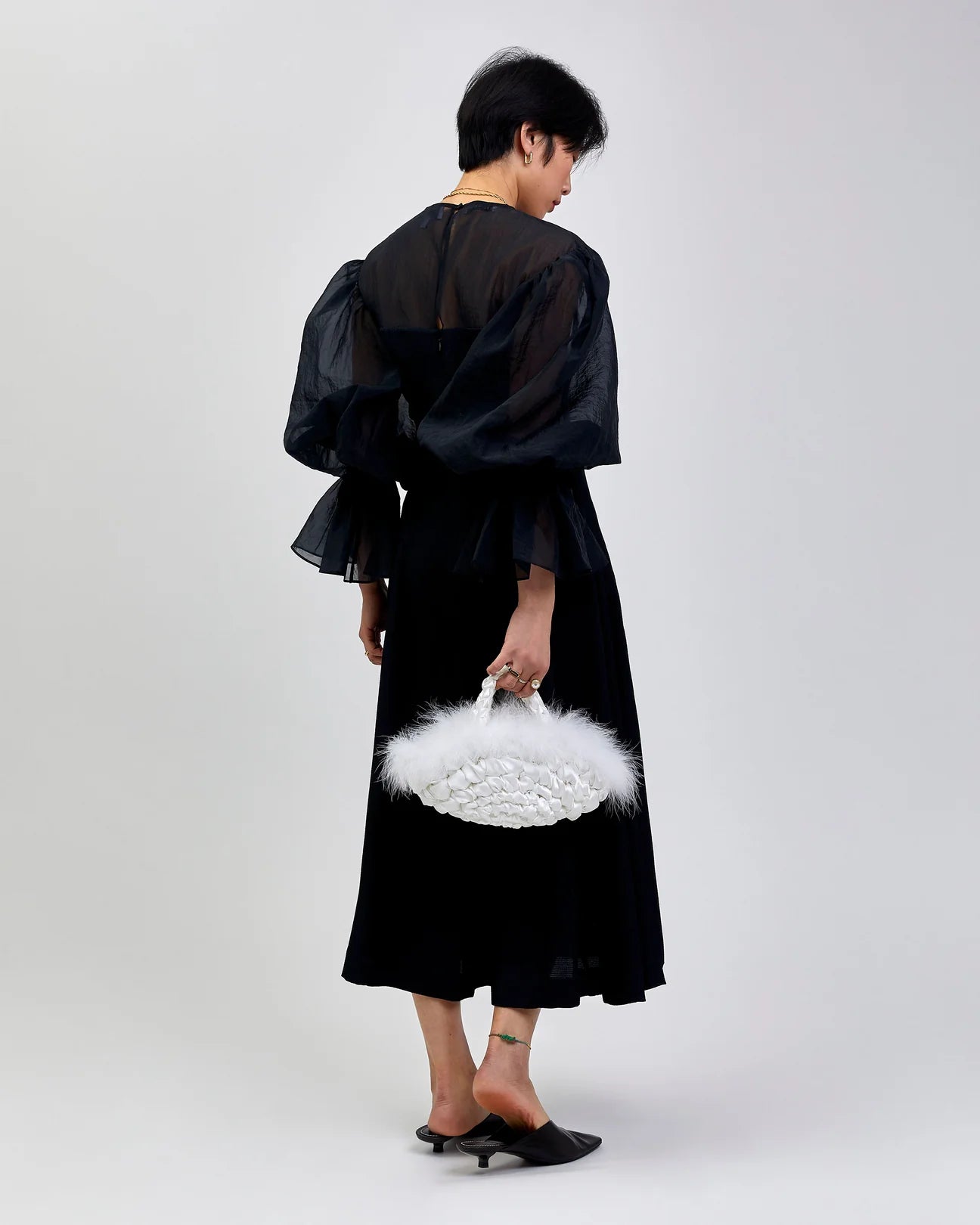 woman holding nest feather handbag in white
