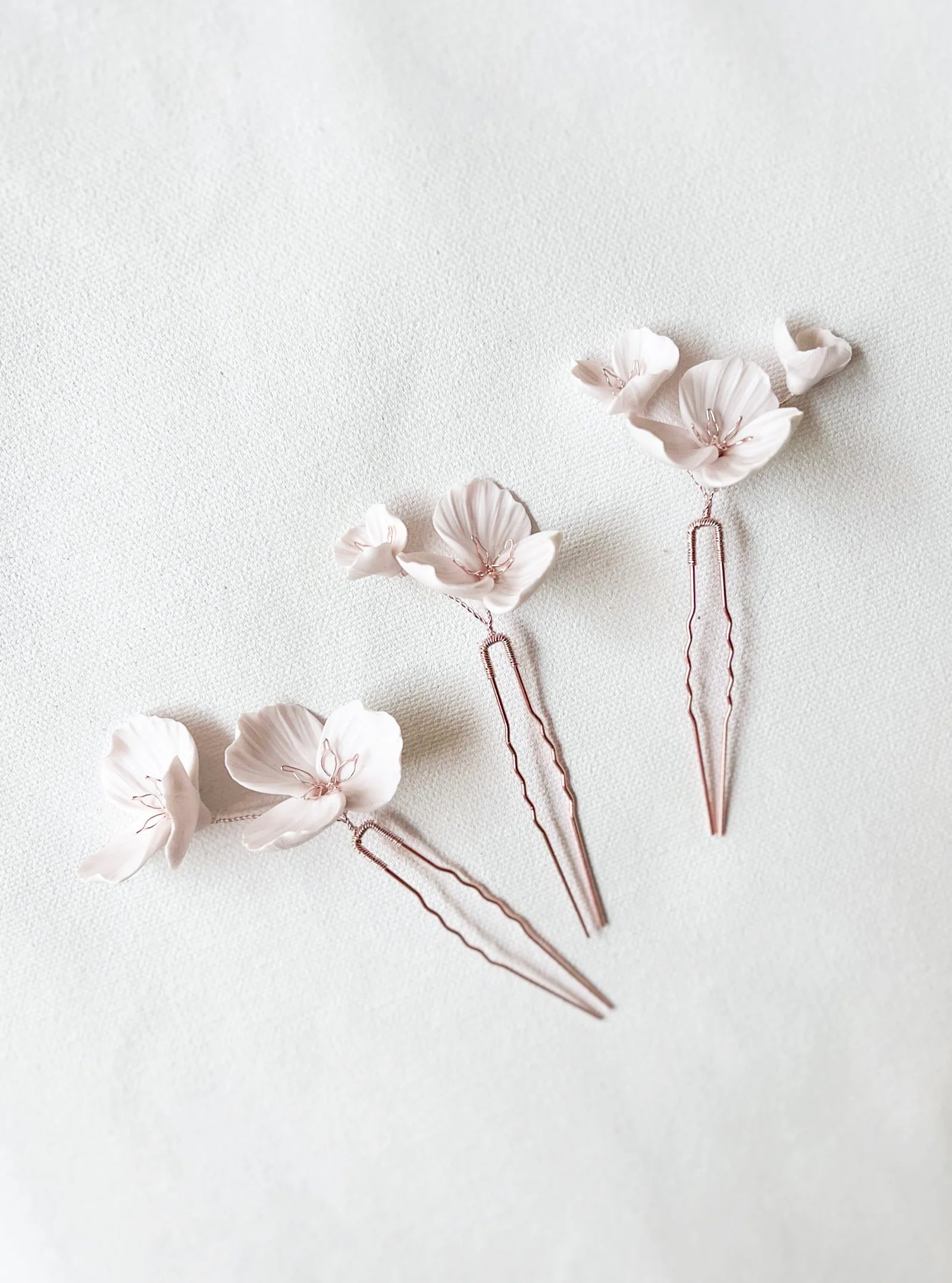 Three floral hairpins on a light gray background