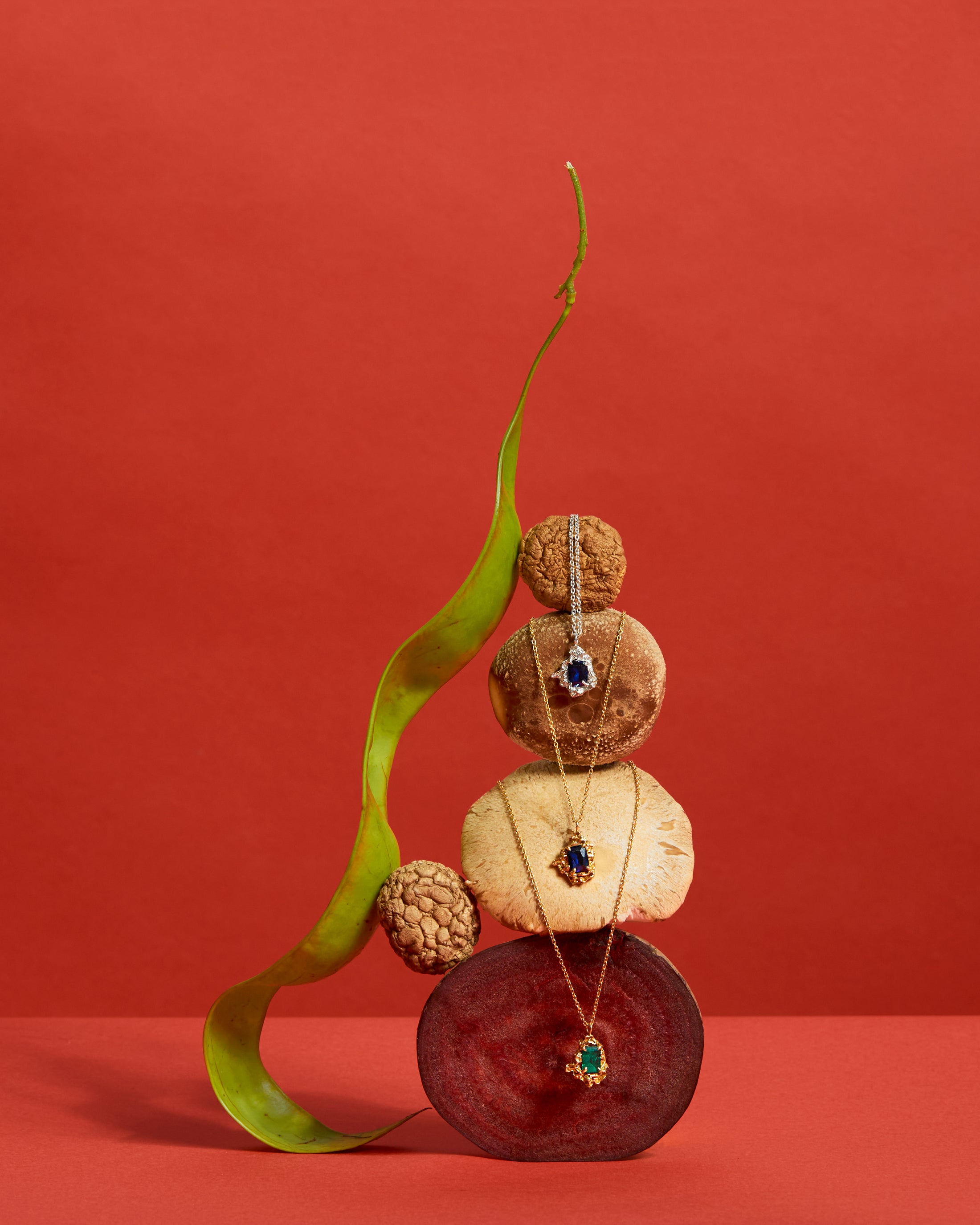 Jewelry displayed on a decorative stack of stones with a red background