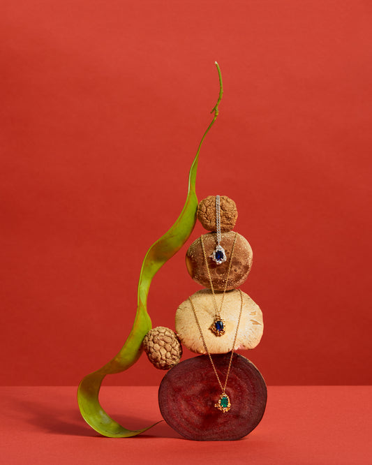 Jewelry displayed on a decorative stack of stones with a red background