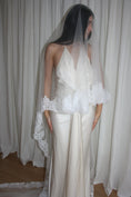 Load image into Gallery viewer, person in a wedding dress with a long lace trim veil against a curtain backdrop.
