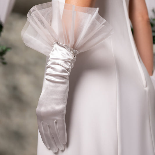 White satin gloves with a decorative bow on a blurred background