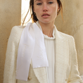 Load image into Gallery viewer, Woman wearing a light-colored blazer with a white hair ribbon against a beige wall.
