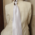 Load image into Gallery viewer, Woman wearing a light-colored blazer with a white hair ribbon against a beige wall.
