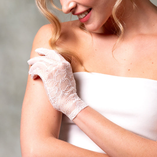 Woman wearing a white lace glove against a neutral background