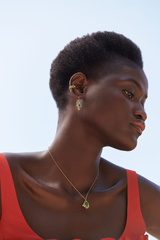 Woman wearing gold earrings and a necklace with a clear blue sky background